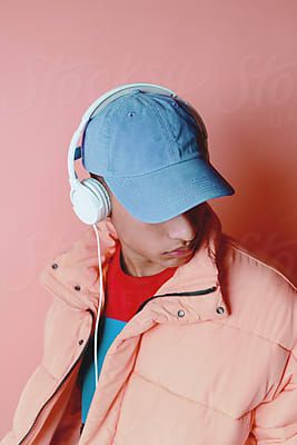 Portrait of a young man listening music with pink coat over pink background. by Leandro Crespifor S…