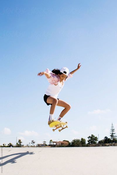 Stylish teen-girl make an ollie in the skatepark on the blue sky background.