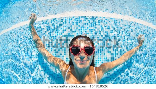 Underwater woman portrait with heart sunglasses in swimming pool.