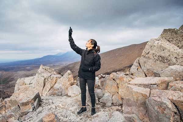 A girl, lost in the mountains tries to get reception on her smartphone.