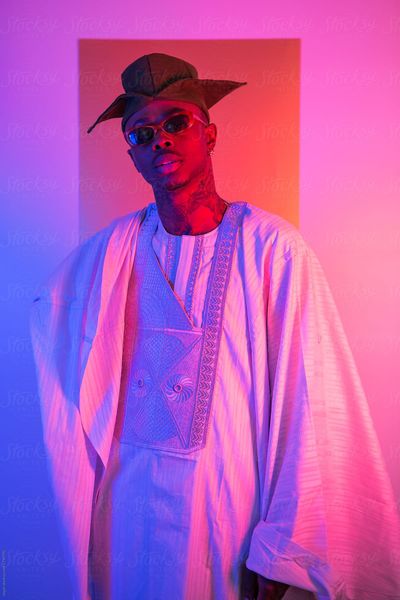 Cool young guy in traditional nigerian clothing and hat with brightly coloured lighting