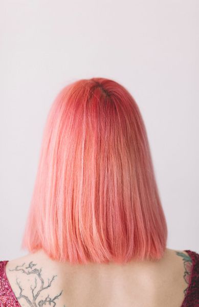 portrait of young woman from behind with pink hair and tattoo