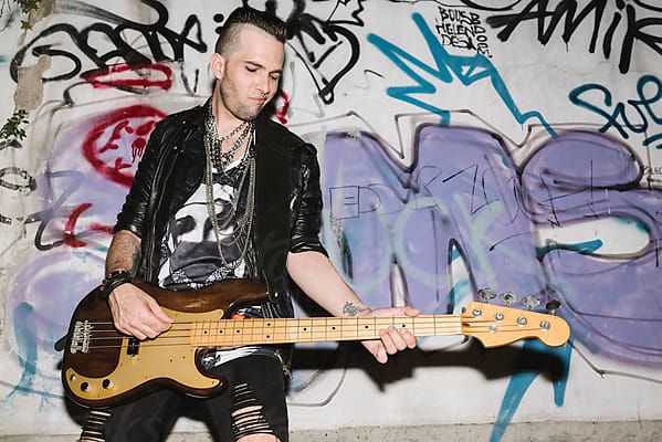 Punk rocker playing bass guitar at the club by simonfor Stocksy United