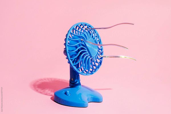 a blue electric fan on a pink background