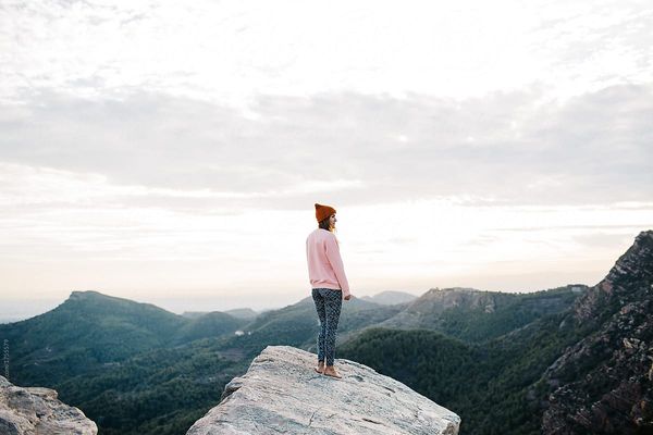 Back view of pretty woman watching beautiful view from the top of the mountain.