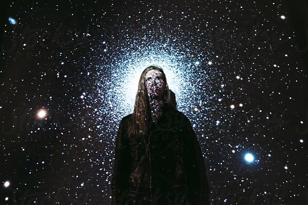 Young man with stars and galaxies projected on him by Rob and Julia Campbellfor Stocksy United