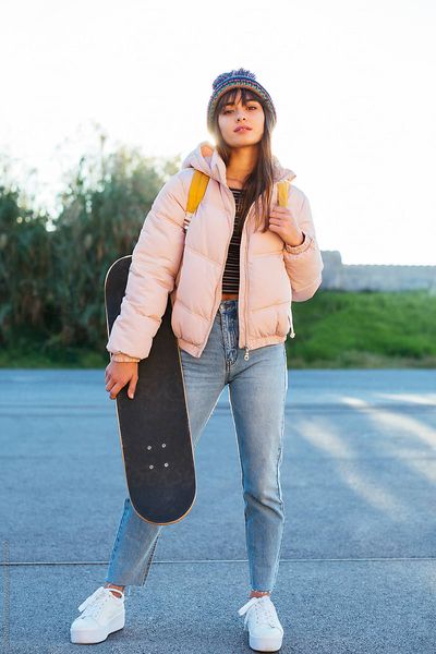Portrait of a girl with a skate on the street in a winter day.
