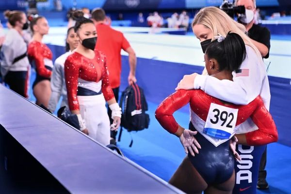 Simone Biles is consoled after competing on the vault and withdrawing from competition in the women…