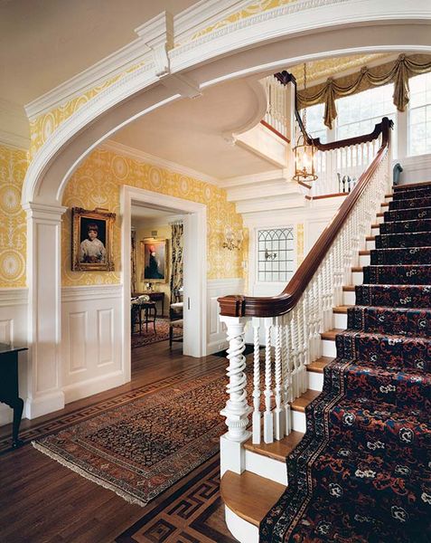 A quintessential Colonial Revival entrance hall is complete with a raised-panel wainscot and bold m…