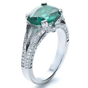 A large Chatham emerald mounted in a custom split shank and accented by rows of bright-cut-set diam…