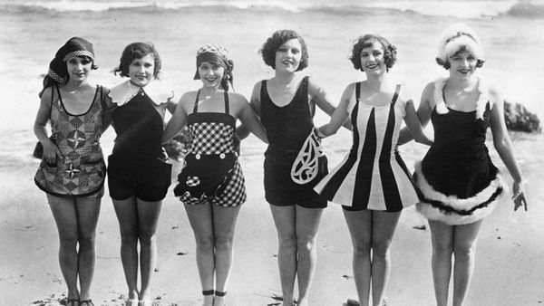 circa 1929: A row of women showing off some unusual and original swimwear on the beach. (weather.co…