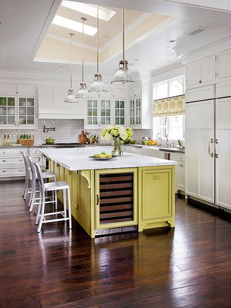 Oak flooring in an ebony stain anchors this elegant kitchen and provides contrast to the white wall…