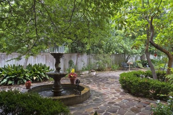 A New Orleans-style courtyard with flagstone pavers and a deep fountain pond populated with koi mak…