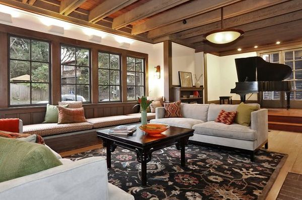 The grand living room of the two-story Craftsman home has a bay window with a window seat next to t…