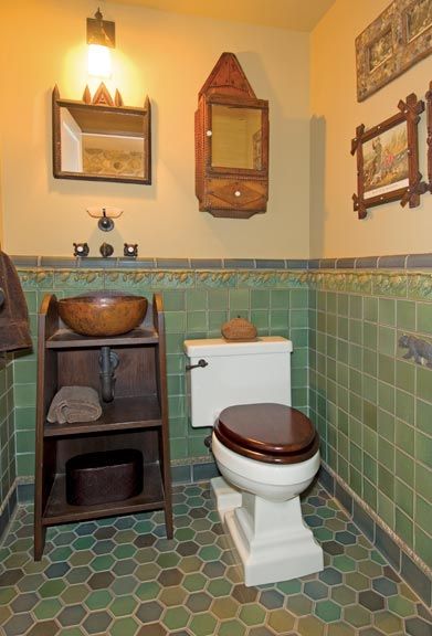 Deep greens and browns soften the downstairs powder room; vintage tramp-art accessories and pine-co…