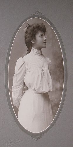 young woman wearing eyeglasses in white shirtwaist.